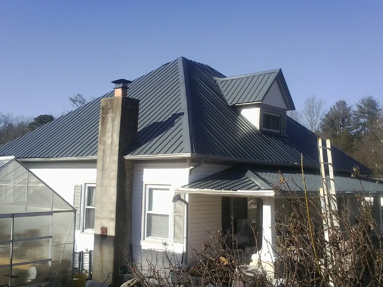 Dark blue standing seam metal roof on a white farmhouse with dormer — Slate & Tile Roof Repair by Roofing Brothers in Water View