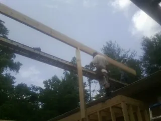 Carpenter setting a ridge beam over a new addition frame — Ice Dam Removal by Roofing Brothers in Water View