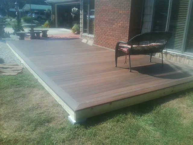 New wood deck and wicker chair beside a brick house in Water View