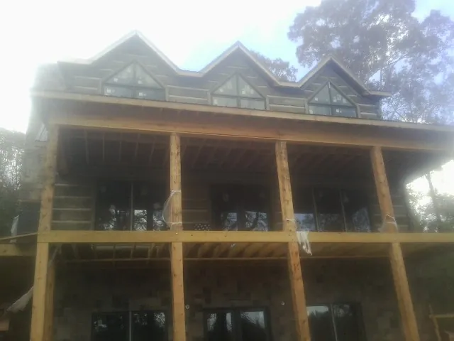 Dormers and porch framing on a large log home under construction — Roof Coating work by our crew in Water View