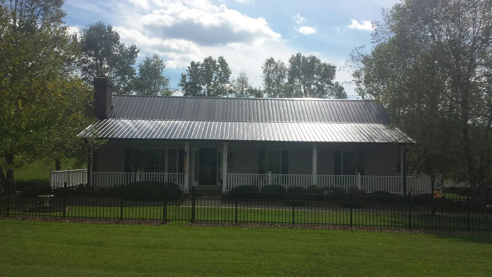 Gray metal roof on a brick ranch with a full width front porch — Gutter Guard Installation work by our crew in Water View
