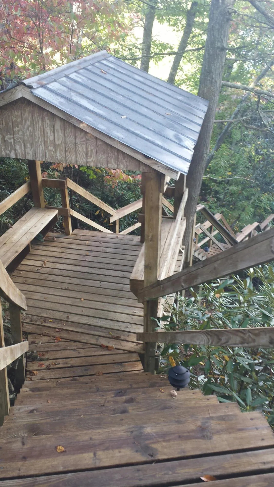 Metal roofed shelter over wooden steps on a wooded walkway — Skylight Repair & Installation work by our crew in Water View